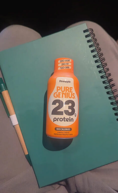 Pure Genius Pineapple protein shot resting on a notebook