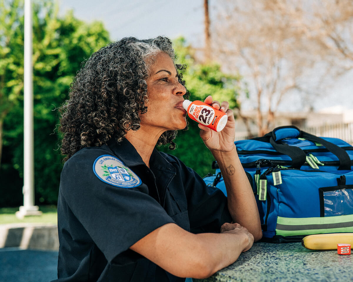 Paramedic drinking a Pure Genius protein shot beside her response bag