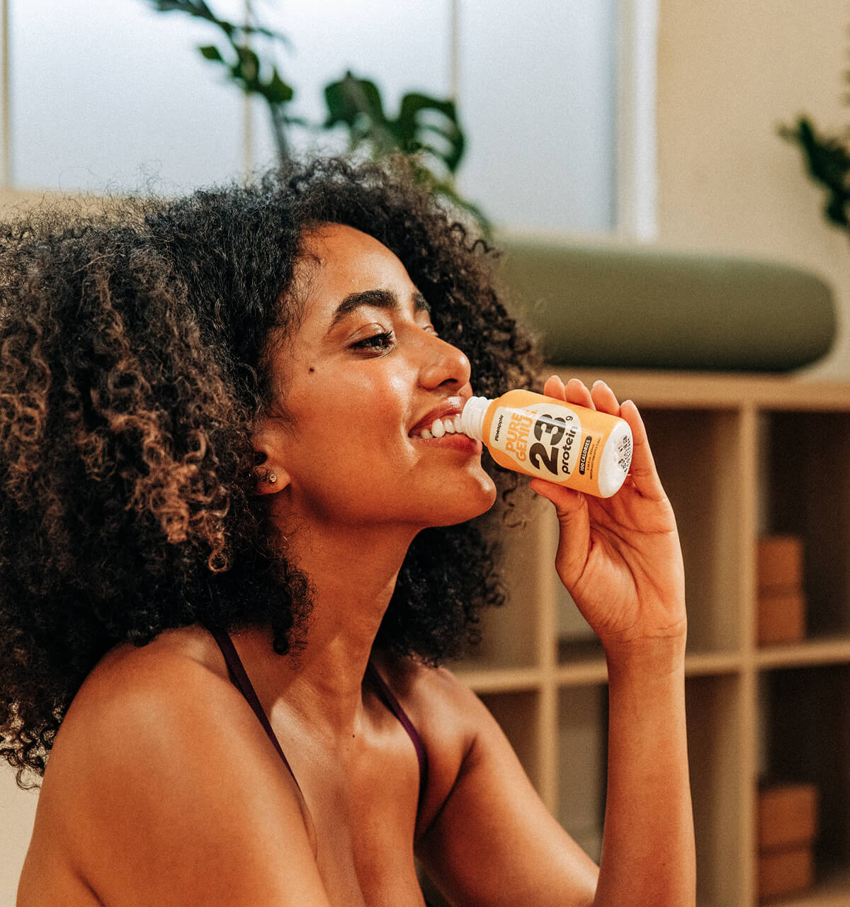 Woman drinking a Pure Genius protein shot in her living room
